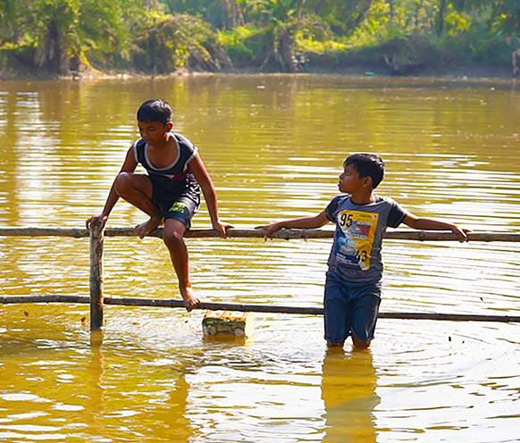Two boys standing on a pond