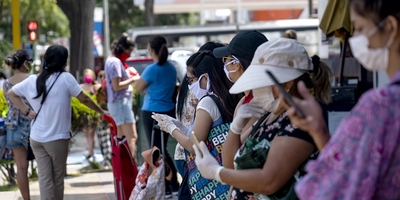 Image of people in masks and using mobile technology in outdoor location